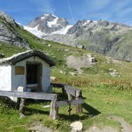 Kleine Hütte mitten auf dem Weideland, eingezäunt mit Holzlatten. Tour Mont Blanc West. Wanderferien mit Eurotrek.