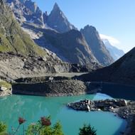 Mont-Blanc hinter türkisfarbenem Bergsee Türkisfarbener Bergsee mit Mont-Blanc-Massiv, das dramatisch im Hintergrund unter strahlend blauem Himmel aufragt, umgeben von felsigem Gelände.