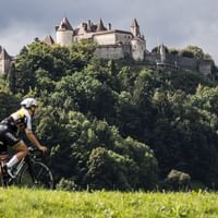 Radfahrer vor einem dicht bewaldeten Hügel mit Schloss