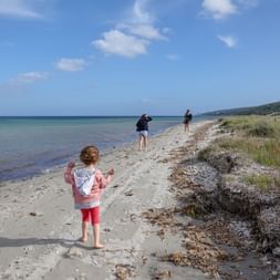 Zwei Frauen und ein Kind befinden sich auf einem kleinen Strand auf Sardinien.