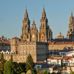 Die Kathedrale von Santiago de Compostela mit ihren charakteristischen barocken Türmen über historischen Steingebäuden und roten Ziegeldächern.