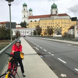 Prisca à vélo sur le pont, devant la cathédrale Saint-Étienne de Passau.