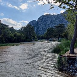 Fluss mit Bäumen am Ufer vor türkischer Bergkulisse