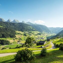 Blick auf ein Dorf im Tal auf dem Alpenpanorama Weg