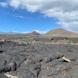 Auf Lavafeldern auf El Hierro sieht man im Hintergrund den Vulkan.