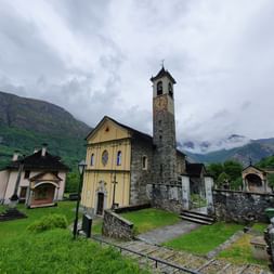 Die Kirche im Dorf von Aurigeno steht auf einer grünen Wiese.