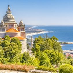 Basilika Santa Luzia mit verzierten Kuppeln mit Blick auf die Atlantikküste von Viana do Castelo, umgeben von üppigen grünen Bäumen.
