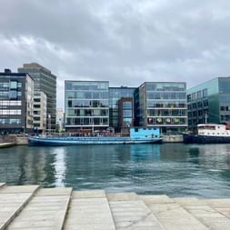 Vue du front de mer de Malmö montrant des immeubles de bureaux modernes en verre le long du port avec des bateaux amarrés dans l'eau.