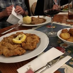 Ein Tisch mit panierem Schnitzel, Bratkartoffeln und Braten mit Knödel. Das muss ein Deutsches Restaurant sein.