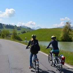 two cyclists ride relaxed along the river