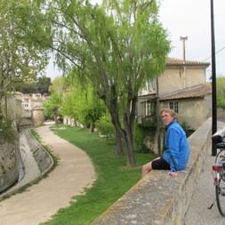 Günther assis sur un mur avec vue sur un chemin et des arbres en Provence