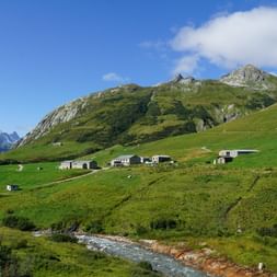 Grüne Wiesen und einige Häuser auf der Mont Blanc West Tour. Wanderferien mit Eurotrek.