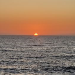 Orange Sonne geht am Horizont über ruhigem Meer bei Vila do Conde unter. Der Himmel leuchtet in warmen Orange- und Goldtönen.