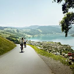 Two cyclists on a side road, riding downhill towards Lake Zug.