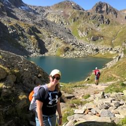 Nina d'Eurotrek se tient devant un lac de montagne lors de sa randonnée sur le sentier des Quatre Sources.