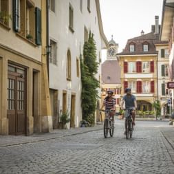 Zwei Velofahren fahren durch die Altstadt von Murten mit dem Velo.