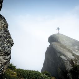 Ein Wanderer steht ganz alleine auf der Felsspitze.
