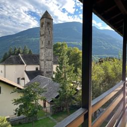 Von einem Balkon sieht man auf eine Steinkirche in Olivone.