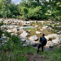 Wanderer mit Rucksack blickt auf einen Fluss
