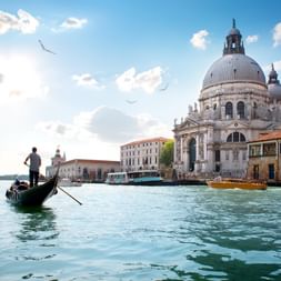 La cathédrale Santa Maria della Salute à Venise avec ses dômes baroques distinctifs, vue depuis le Grand Canal avec une gondole au premier plan.