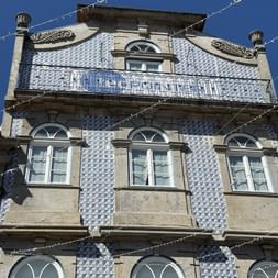 Portugiesisches Gebäude in Viana do Castelo mit blau-weißen Azulejo-Kacheln, Bogenfenstern, verziertem Balkon und dekorativem Steinwerk vor blauem Himmel.