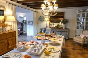 Table de buffet petit-déjeuner au Can Quatre Sóller avec plateaux de charcuterie, fromage et fruits dans une salle rustique avec poutres.