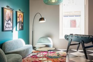 Farbenfroher Aufenthaltsraum im Hotel Labe Tours mit türkisfarbenem Sofa, Tischkicker, Schachbrettboden und Pop-Art-Postern an türkiser Wand.