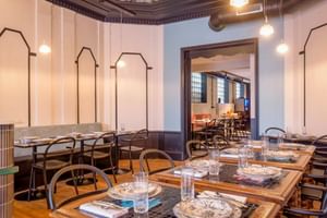 Modernes Restaurantinterieur mit gedeckten Tischen, Metallstühlen, dekorativer Decke und weißen Paneelwänden im Hotel Labé Tours.
