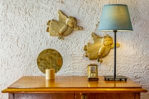 Holzkommode mit Lampe, Spiegel und Engelfiguren an weißer Strukturwand im Le Valli Agriturismo in Casciana Terme, Italien.
