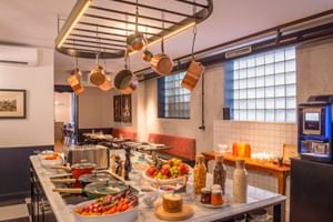 Frühstücksbuffet im Hotel Labe Tours mit frischem Obst, Gemüse, Müsli und Getränken auf einer Marmorplatte unter einem Topfhänger.