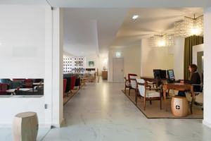 Moderne Hotelrezeption im Furadouro Beach & Spa mit Marmorböden, Kristallleuchtern, Holztheke und Mitarbeiter am Computer.