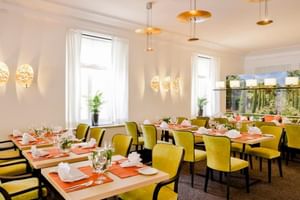 Modernes Restaurant-Interieur mit gelben Polsterstühlen um Holztische mit orangen Platzsets und weißen Servietten.