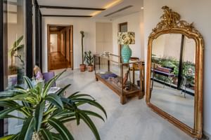 Eleganter Spa-Eingang im Hotel Regina Adelaide mit großem goldenen Zierspiegel, Marmorböden, sichtbaren Deckenbalken und Tropenpflanzen.