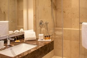 Elegantes Badezimmer im Alte Post Konstanz mit Marmorwänden, Glasdusche, dunklem Marmor-Waschtisch, weißen Handtüchern.