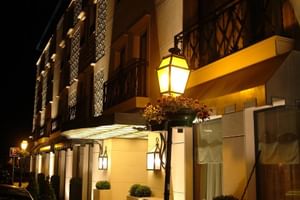 Nachtansicht der Fassade des Hotel Moliceiro Aveiro mit warmer Beleuchtung, dekorativen Balkonen, Laternen und Eingangsüberdachung.