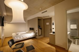 Zeitgenössisches Hotel-Doppelzimmer mit weißem Bett, Holzböden, modernen Stühlen und eigenem Bad im Giardino Verdi Riva.