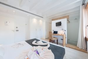Modernes Hotel-Doppelzimmer mit weißem Bett, Holzschreibtisch, Glasdusche, Einbauschränken und zeitgemäßem Design in neutralen Tönen.