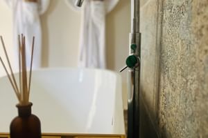 Modernes Badezimmer im Blackwell House mit Chromarmatur, Holztablett, Raumduft und weißen Bademänteln an der Wand.
