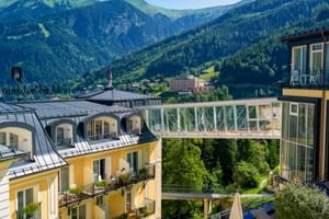 Dachterrassenblick im Salzburger Hof in Bad Gastein mit Glasbrücke zwischen Gebäuden, umgeben von grünen Alpenbergen.