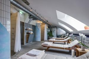 Moderner Spa-Ruhebereich mit Holzliegen, weißen Orchideen, Oberlichtern und Saunaeingang im SEEhotel Friedrichshafen.