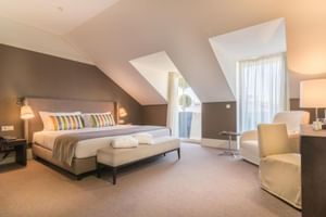 Modernes Dachgeschoss-Doppelzimmer im Universal Boutique Hotel mit Dachschräge, großem Bett, gestreiften Kissen und Dachfenstern.
