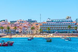 Hotel Baia in Cascais, Portugal, ein modernes blaues Hotelgebäude am Wasser mit traditioneller portugiesischer Architektur und Booten in der Bucht.