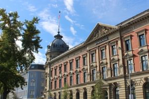 Historisches Hotel Alte Post Gebäude in Konstanz mit roter Backsteinfassade, kunstvoller Architektur und markanter Kuppel mit Schweizer Flagge.