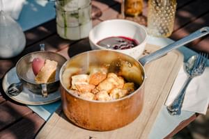 Kaiserschmarrn in einer Kupferpfanne mit karamellisiertem Zucker, serviert mit Beerenkompott und Eis im Hotel Post am See in Traunkirchen.