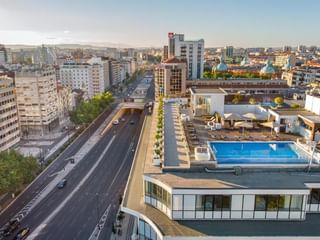 Luftaufnahme des Dachpools und der Terrasse des Hotel Jupiter Lisboa mit Blick auf Lissabons Stadtbild mit modernen Gebäuden.