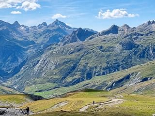 Weites Bergpanorama in der Mont Blanc Region mit schneebedeckten Gipfeln, grünen Alpentälern und dramatischem Felsgelände unter blauem Himmel.