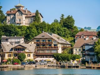 Seeblick auf Hotel Post am See in Traunkirchen mit traditioneller Alpenarchitektur, Holzbalkonen und Booten am Steg.