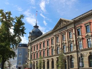 Historisches Hotel Alte Post Gebäude in Konstanz mit roter Backsteinfassade, kunstvoller Architektur und markanter Kuppel mit Schweizer Flagge.