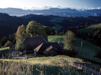 Ein kleiner Bauernhof sitzt inmitten ruhiger Natur mit Aussicht auf die Alpen im Emmental im Kanton Bern.