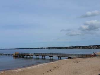 Ein langer Holzsteg ragt ins Wasser am Strand in Ängelholm in Schweden.